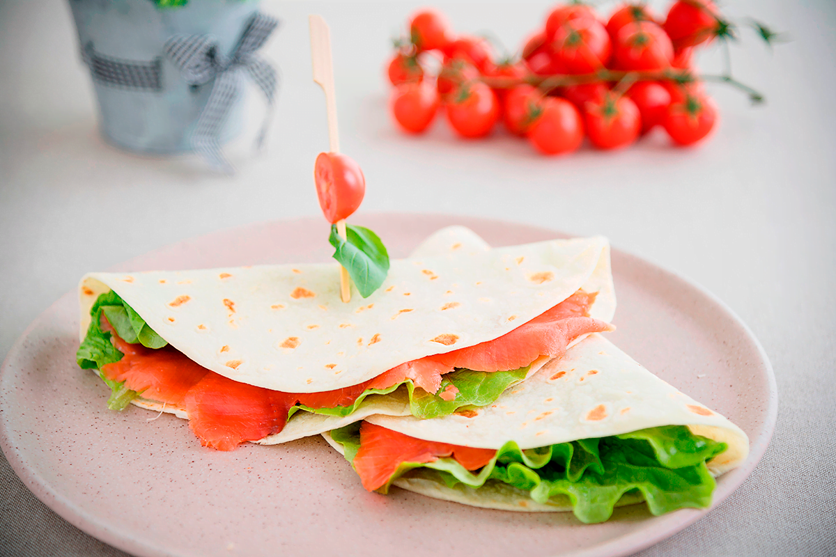 Piadina con insalata croccante, salmone affumicato, rondelle pomodoro e basilico